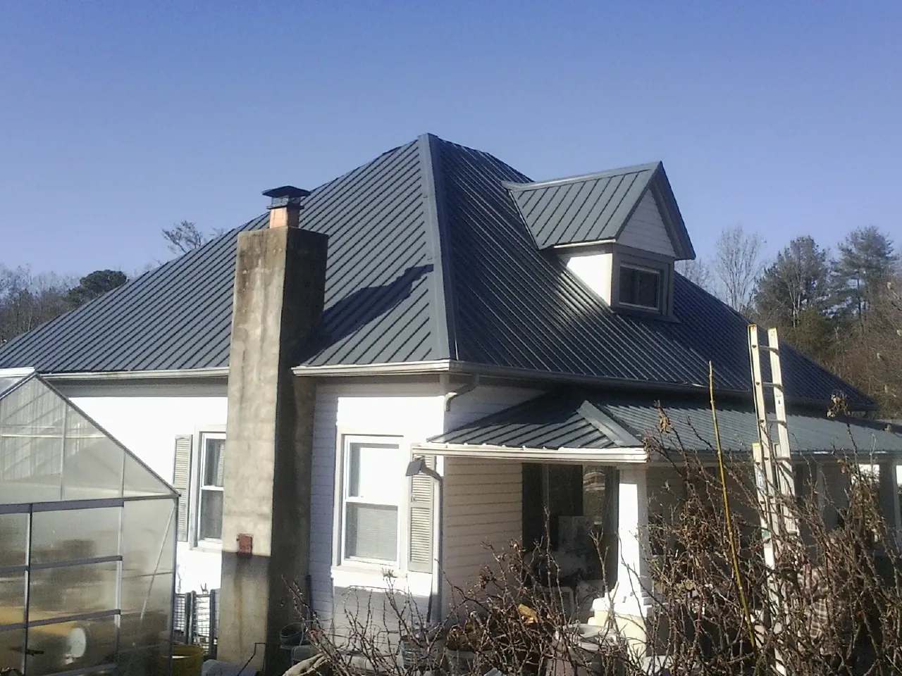 Dark blue standing seam metal roof on a white farmhouse with dormer — Slate & Tile Roof Repair by Roofing Brothers in Susanville