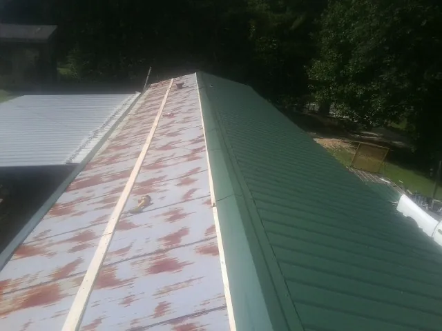 Old rusted panels beside newly installed green metal roofing — Wind Damage Roof Repair by Roofing Brothers in Susanville