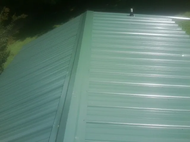 New green metal panels meeting at the ridge of a roof — Flat Roof Repair work by our crew in Susanville