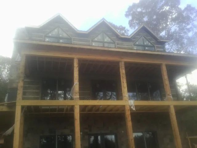 Dormers and porch framing on a large log home under construction — Roof Coating work by our crew in Susanville