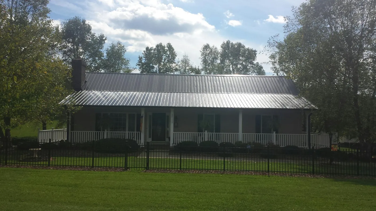 Gray metal roof on a brick ranch with a full width front porch — Gutter Guard Installation work by our crew in Susanville