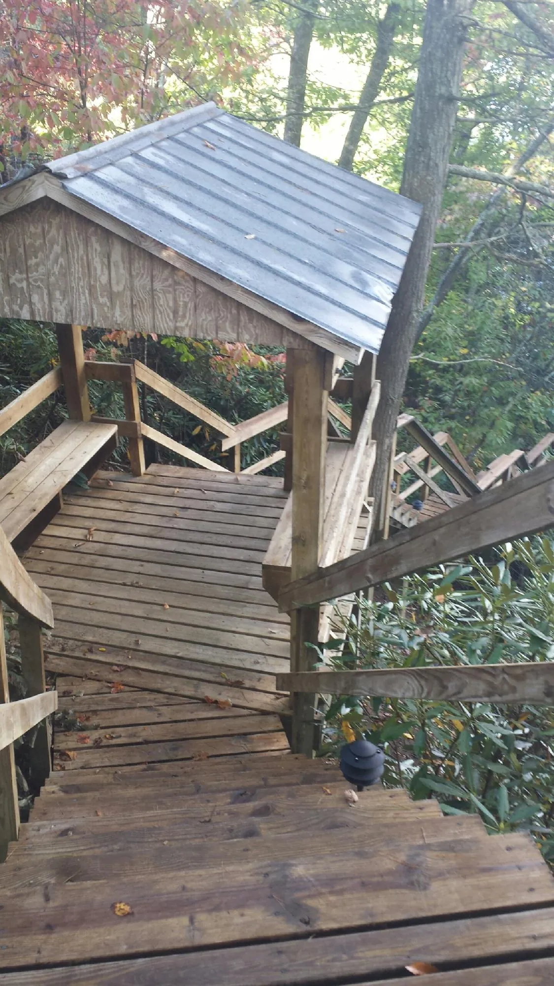 Metal roofed shelter over wooden steps on a wooded walkway — Skylight Repair & Installation work by our crew in Susanville