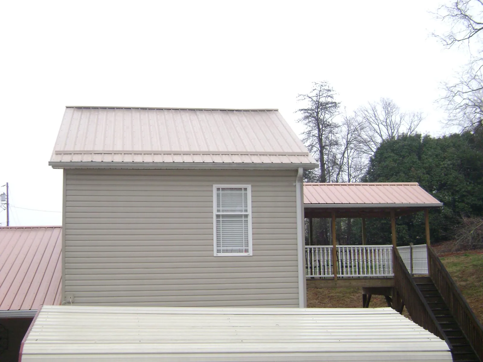 Tan metal roofs on a two story addition and attached porch, from a Roof Replacement job in Susanville