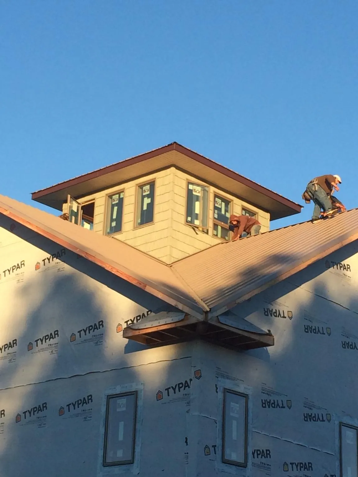 Roofers working around a rooftop cupola on a new metal roof at sunset — Roof Waterproofing in Susanville by Roofing Brothers